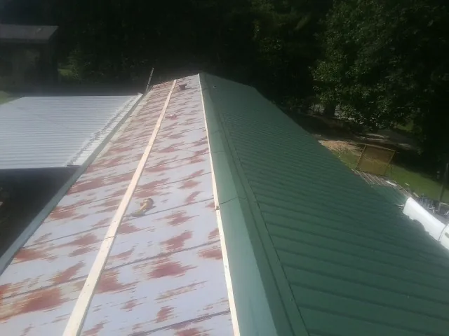 Old rusted panels beside newly installed green metal roofing — Wind Damage Roof Repair by Roofing Brothers in Cuthbert