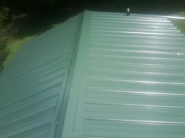New green metal panels meeting at the ridge of a roof — Flat Roof Repair work by our crew in Cuthbert