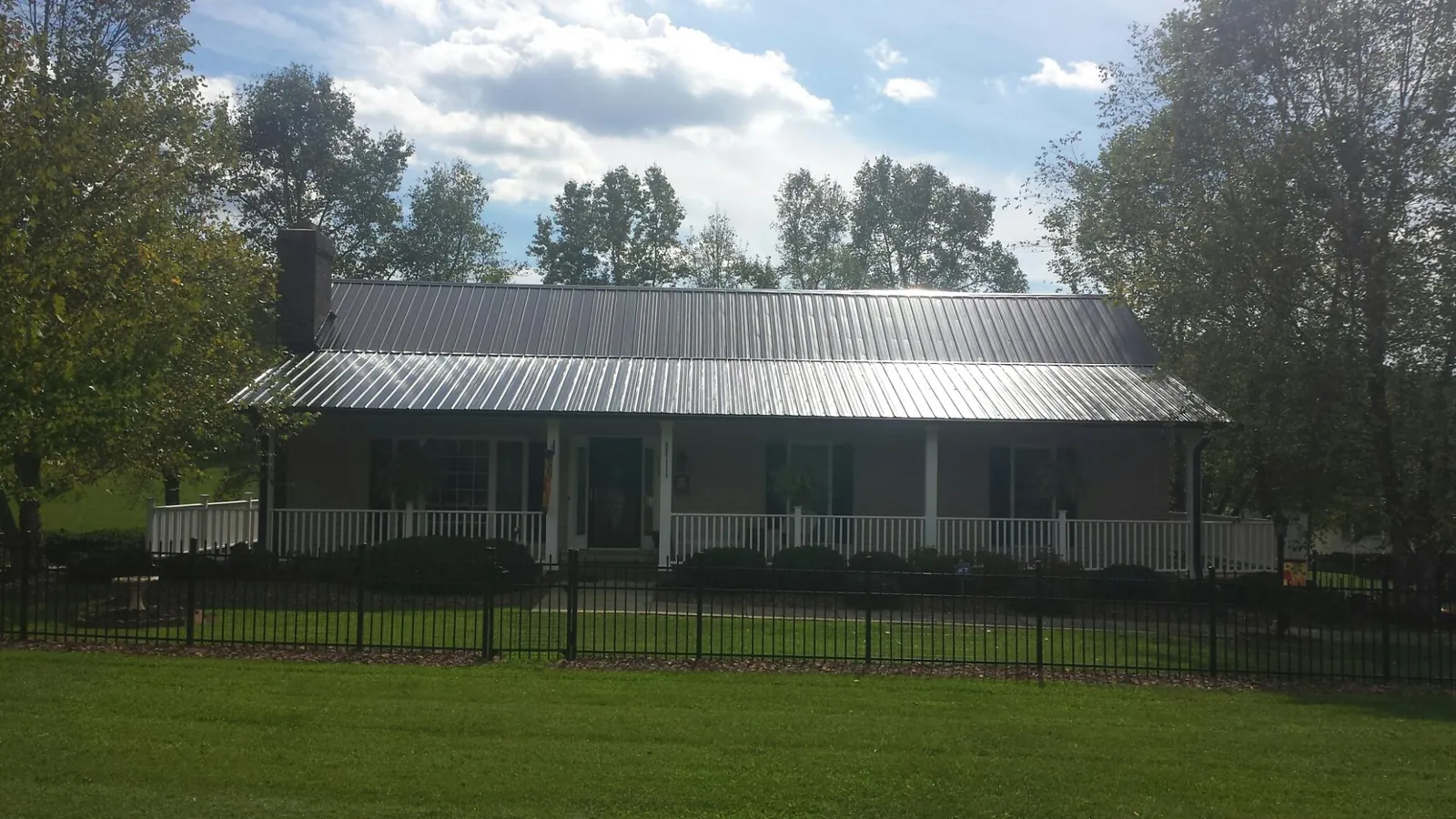Gray metal roof on a brick ranch with a full width front porch — Gutter Guard Installation work by our crew in Cuthbert