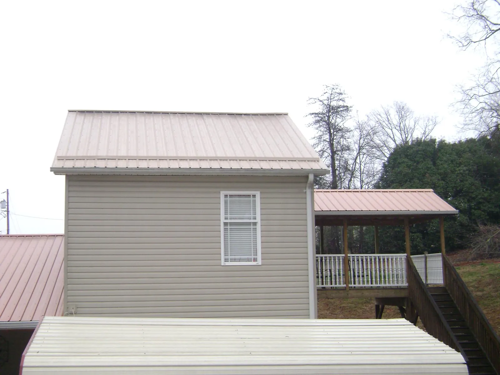 Tan metal roofs on a two story addition and attached porch, from a Roof Replacement job in Cuthbert