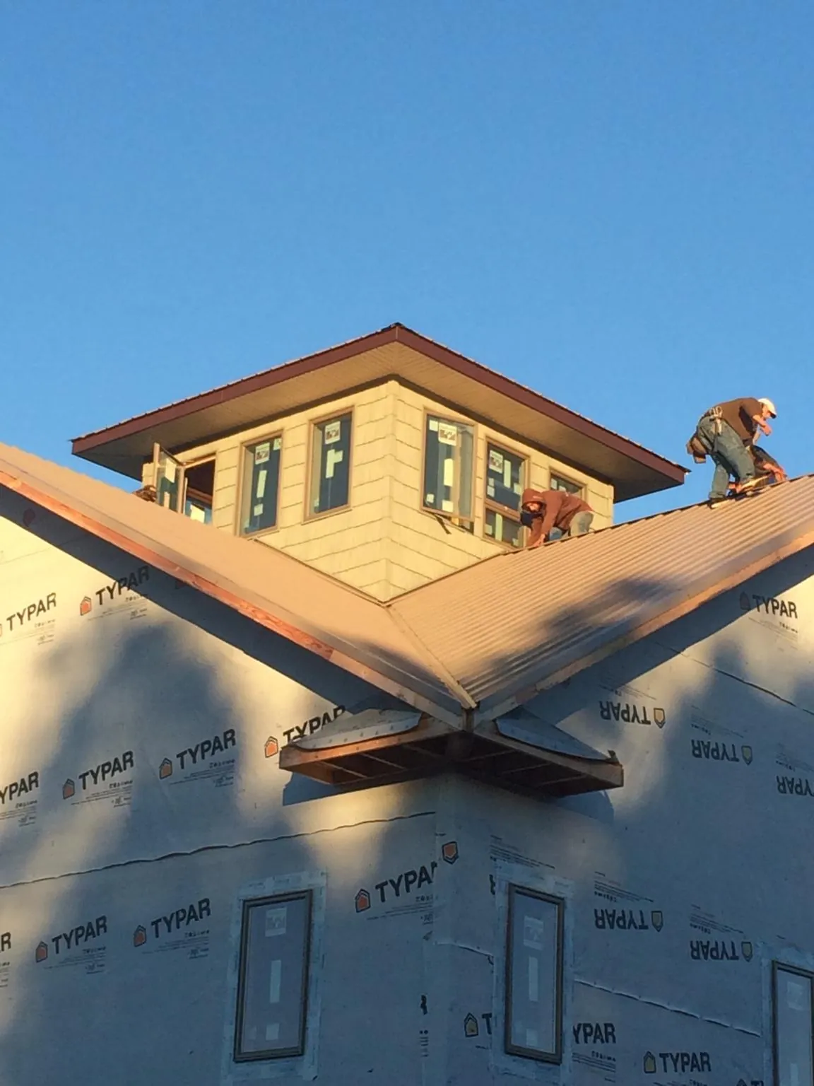 Roofers working around a rooftop cupola on a new metal roof at sunset — Roof Waterproofing in Cuthbert by Roofing Brothers